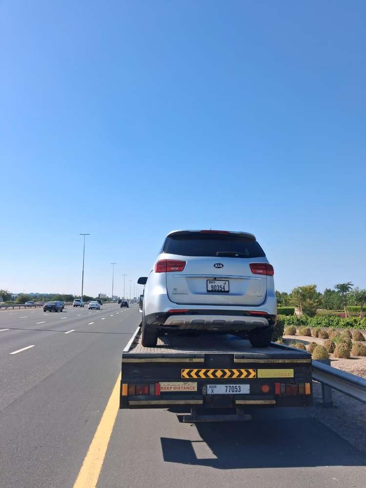 Zubair Recovery flatbed transporting a silver Kia SUV on a Dubai highway
