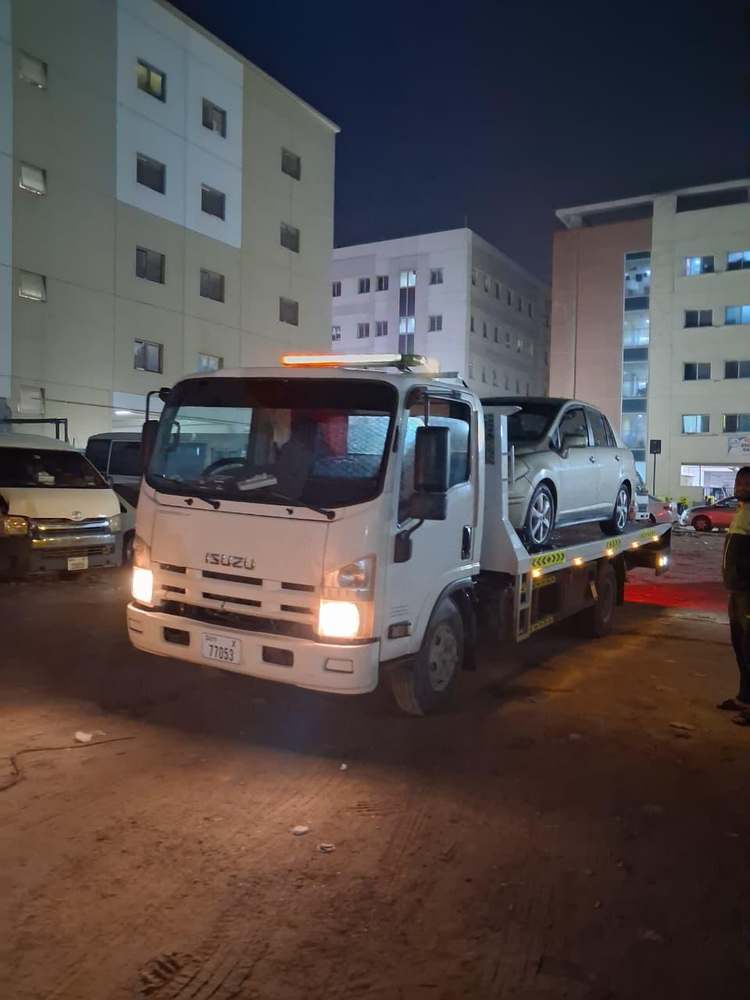 Zubair Recovery white Isuzu flatbed truck parked at night