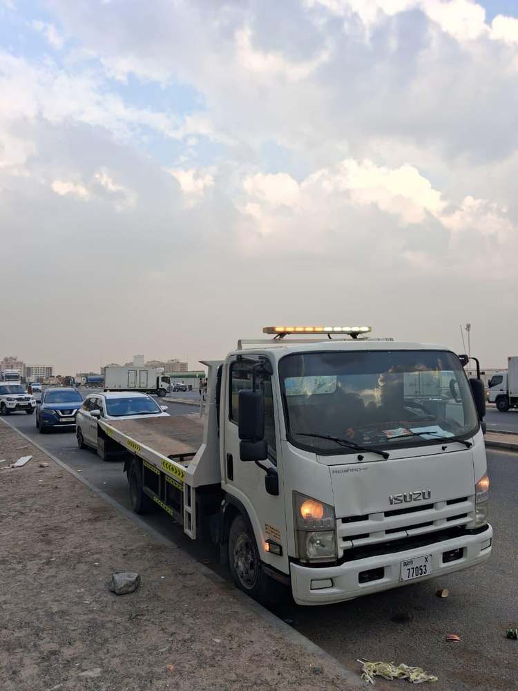 Zubair Recovery white Isuzu flatbed truck in daylight