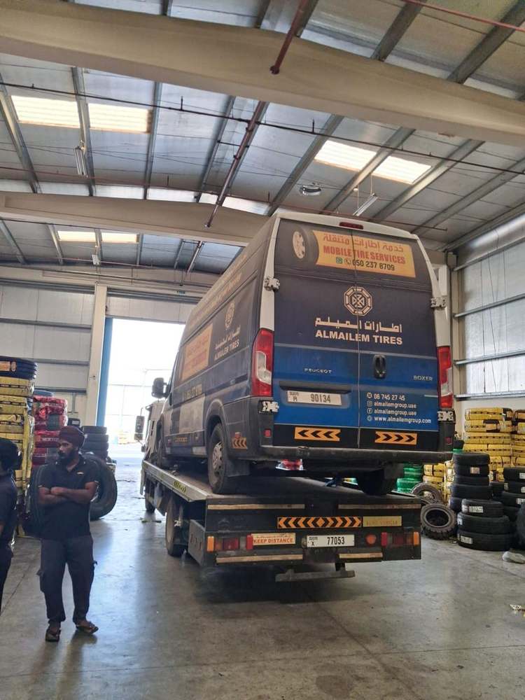 Commercial Peugeot van loaded on a recovery flatbed inside a tire warehouse